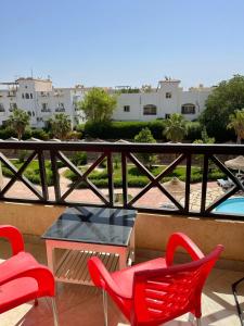 um pátio com cadeiras vermelhas e uma mesa na varanda em Two Bedroom at Sunny Lakes Resort em Sharm el Sheikh