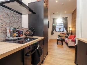 a kitchen with a stove top oven next to a living room at The Dynar in Helston