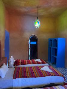 a bedroom with two beds and a chandelier at Riad Aicha & Camel Trekking in Merzouga