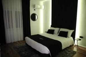1 dormitorio con 1 cama grande con almohadas blancas y negras en Dark Boutique Hotel, en Tirana