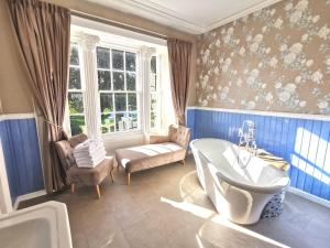 a bathroom with a tub and a chair and a sink at Lunan House in Arbroath