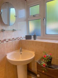 a bathroom with a sink and two windows at 303 Alexandra Avenue HA2 9DX in Pinner