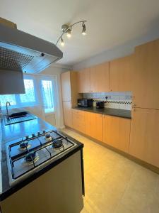 cocina con fogones y encimera en 303 Alexandra Avenue HA2 9DX en Pinner