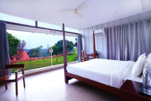a bedroom with a bed and a large window at Ravishing Retreat Resort in Rāmanagaram