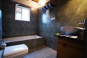 a bathroom with a tub and a sink and a toilet at Ravishing Retreat Resort in Rāmanagaram
