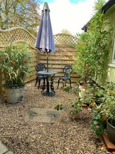 einen Regenschirm, zwei Stühle und einen Tisch im Garten in der Unterkunft Little Limes an Adorable little Suffolk getaway with outside space near Woodbridge in Eyke