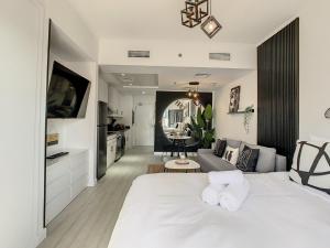 Luxury Modern Studio in JLT with Amazing View & Rooftop Pool - sleeps 3 في دبي: غرفة نوم بسرير ابيض وغرفة معيشة