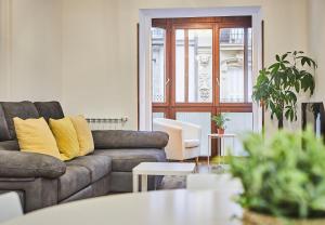 ein Wohnzimmer mit einer grauen Couch und gelben Kissen in der Unterkunft Txindoki by Basque Homes in San Sebastián