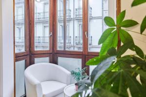 ein weißer Stuhl in einem Raum mit Fenstern in der Unterkunft Txindoki by Basque Homes in San Sebastián