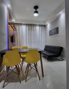 een eetkamer met een tafel en gele stoelen bij Apartamento Com Churrasqueira Maranduba Ubatuba! in Ubatuba