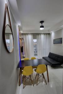 een eetkamer met een zwarte tafel en gele stoelen bij Apartamento Com Churrasqueira Maranduba Ubatuba! in Ubatuba