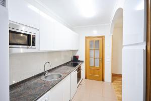 eine weiße Küche mit Spüle und Mikrowelle in der Unterkunft Txindoki by Basque Homes in San Sebastián + 24 Fotos