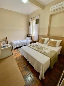 a hotel room with two beds and a table at Grande Hotel Minas Gerais in Siqueira Campos