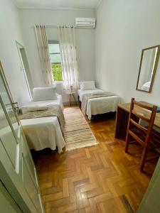 a room with two beds and a wooden floor at Grande Hotel Minas Gerais in Siqueira Campos