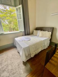 Ce lit se trouve dans un dortoir doté d'une grande fenêtre. dans l'établissement Grande Hotel Minas Gerais, à Siqueira Campos