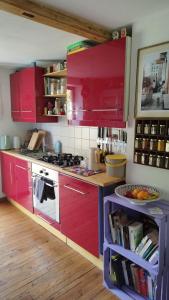 a kitchen with red cabinets and a stove at Atelier & Gardenhouse Glamping in Munich