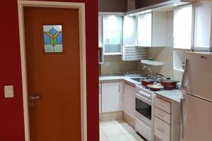 Una cocina con gabinetes blancos y una puerta naranja. en Departamento luminoso amplio y silencioso., en Rosario