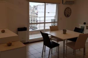 comedor con mesa, sillas y reloj en Departamento luminoso amplio y silencioso. en Rosario