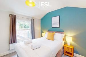 a bedroom with a large bed with a blue wall at 5 Bedroom House - Ideal for Groups & Contractors in Shrewsbury