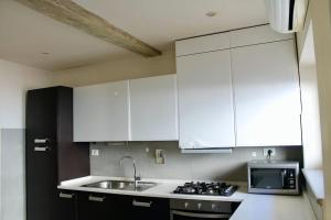 kuchnia z białymi szafkami, zlewem i kuchenką mikrofalową w obiekcie Modern 3BR Near Santa Maria Novella Station we Florencji