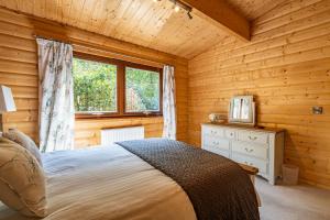 Dormitorio con cama y ventana en una cabaña de madera en Screel View, en Kippford