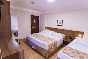 Cette chambre comprend deux lits et une télévision. dans l'établissement JR Hotel Ribeirão Preto, à Ribeirão Preto