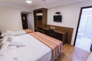 um quarto com uma cama, uma secretária e uma televisão em JR Hotel Ribeirão Preto em Ribeirão Preto