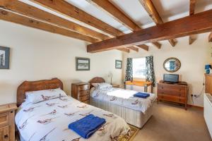two beds in a room with wooden ceilings at Chapelton Coachman's Cottage in Kirkcudbright