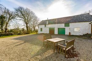 a table and two benches in front of a building at Chapelton Coachman's Cottage in Kirkcudbright