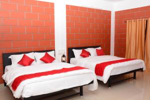 2 bedden met rode kussens in een kamer bij ClayNest Resorts in Kuttālam