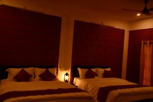 twee bedden in een slaapkamer met rode muren bij ClayNest Resorts in Kuttālam