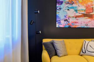 a yellow couch in a living room with a painting at Lemonade - Stylish 1BR Apartment in Obor District in Bucharest