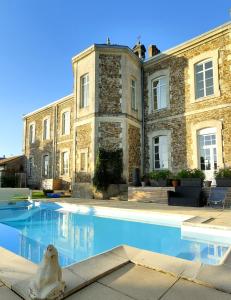 uma casa com piscina em frente a um edifício em La Maison D'Olivier em Mesnard-la-Barotière