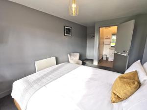 a bedroom with a large white bed with two chairs at Lunan House in Arbroath