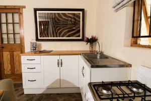 een witte keuken met een wastafel en een fornuis bij Wild Olive Cottage in Graaff-Reinet