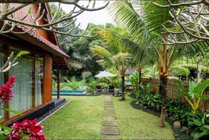 a garden in front of a house with palm trees at Govinda Villas in Penginyahan