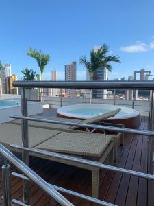 einen Balkon mit einem Pool, einem Tisch und einer Bank in der Unterkunft Flat Manaíra Apart Hotel in João Pessoa