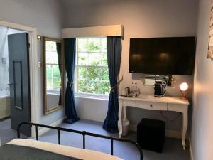 a bedroom with a bed and a desk with a television at Lunan House in Arbroath
