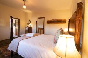 a bedroom with a large white bed with a lamp at Wild Olive Cottage in Graaff-Reinet
