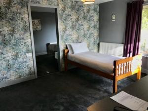 a small bedroom with a bed and a mirror at Lunan House in Arbroath