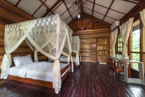sypialnia z łóżkiem z baldachimem w drewnianym domu w obiekcie Borneo Sepilok Rainforest Resort w mieście Sepilok