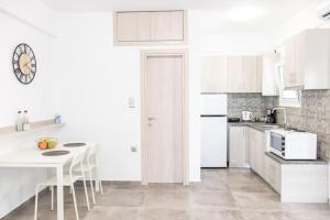 a white kitchen with a table and a clock on the wall at Spacious Flat For Friends & Couples With Balcony in Heraklio Town