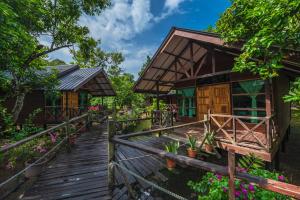 a wooden walkway in front of a house with flowers at Borneo Sepilok Rainforest Resort in Sepilok