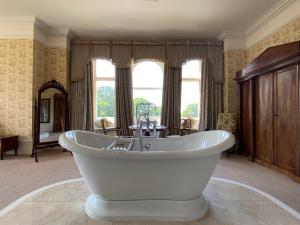 een grote badkamer met een wit bad voor een raam bij Rossington Hall in Doncaster