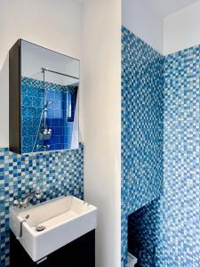 ein blau gefliestes Bad mit einem Waschbecken und einem Spiegel in der Unterkunft Calme, mer et montagne Anglet in Anglet