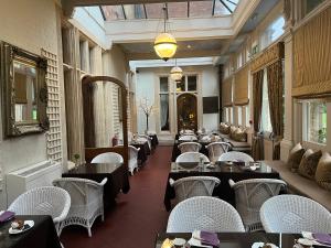 un ristorante con tavoli, sedie bianche e un soffitto di Rossington Hall a Doncaster
