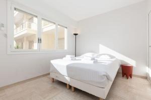 a white bedroom with a white bed and a window at Chic and modern apt with terrace - La Croisette in Cannes