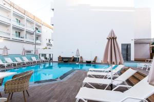a hotel pool with white chairs and a pool table at Kahlua Sea View Suites in Hersonissos