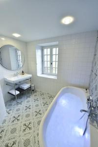 La salle de bains blanche est pourvue d'une baignoire et d'un lavabo. dans l'établissement La Maison Rose, chaleureuse et luxueuse, à Roanne