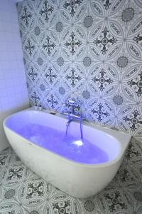 La salle de bains est pourvue d'une baignoire avec de l'eau bleue. dans l'établissement La Maison Rose, chaleureuse et luxueuse, à Roanne